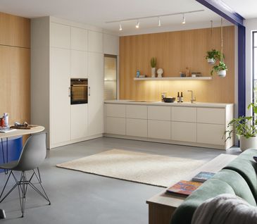 Schüller Küche in L-Form, beigen Fronten und Rückwand in Holzoptik.
