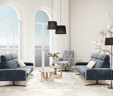 Zwei blaue 2-Sitzer Sofas mit Drehsessel in Blumenmuster in modernem Wohnzimmer.