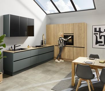 Küchenzeile in Dunkelgrün mit Holzelementen und offenem Essbereich.