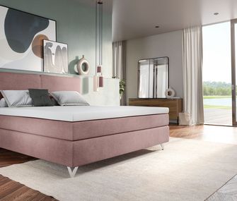 Rosa Boxspringbett vor salbeigrüner Wand in hellem, modernem Schlafzimmer