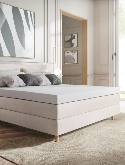 Elegant eingerichtetes Schlafzimmer mit beigem Boxspringbett.