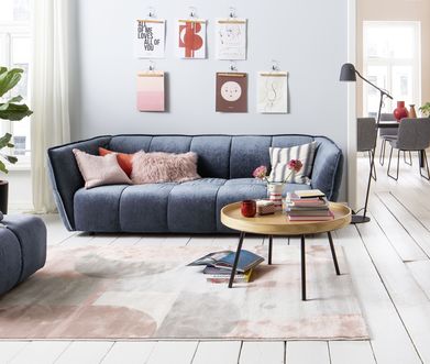 Blaues Sofa mit Beistelltisch aus Holz und blauem passenden Hocker.