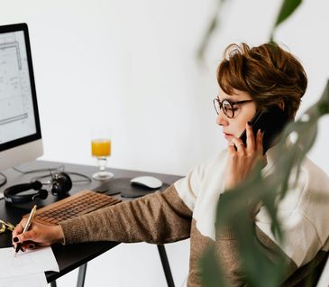 Frau berät am Telefon einen Kunden zur Küchenplanung.