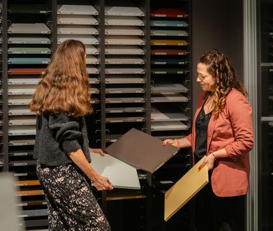 Küchenexpertin zeigt einer Kundin verschiedene Materialien bei Küchenplanung.