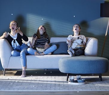 Vogelperspektive auf graues Sofa mit blauen und weißem Kissen vor schwarzem Couchtisch