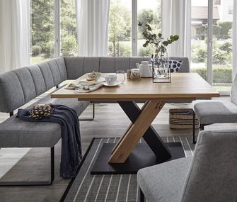 Graue gepolsterte Sitzbank vor einem Esstisch aus Massivholz