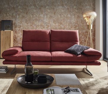 Rotes 2-Siter-Sofa in hellem Wohnzimmer mit moderner Stehleuchte und Couchtisch.