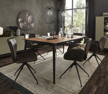 Dunkelbraune Lederstühle um Holz-Esstisch neben grünem Sideboard