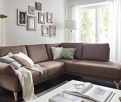 Braunes Ecksofa mit bunten Kissen und einem Couchtisch vor einer weißen Vitrine