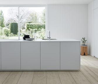 Wer träumt nicht von solch einer Küche? Schlicht-weiße Kücheninsel vor großem Fenster