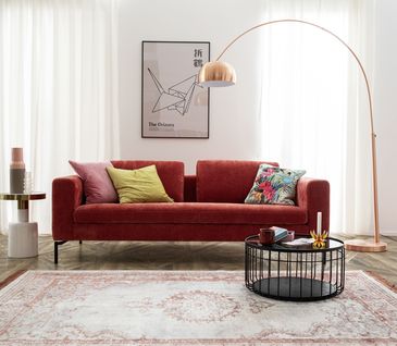 Die Farbe Rot passt in jeden Raum. Glauben Sie nicht? Dann lassen Sie sich jetzt überzeugen. Rotes Sofa in hellem Wohnzimmer mit schwarzem Beistelltisch.