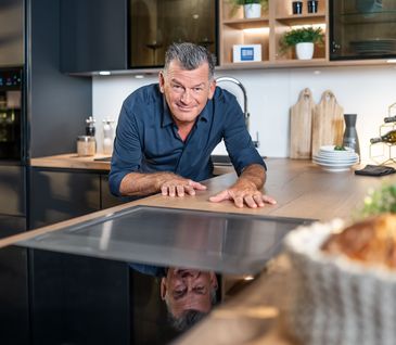 Mark Kühler präsentiert eine Küche mit hochwertigen Materialien und E-Geräten.