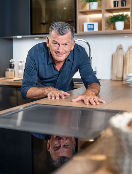 Mark Kühler präsentiert eine Küche mit hochwertigen Materialien und E-Geräten.