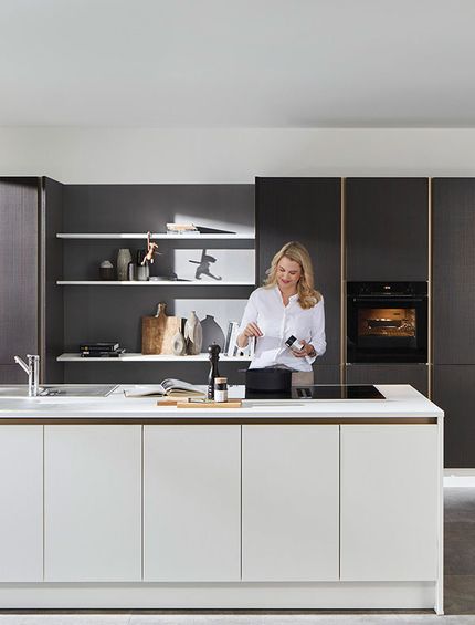 Inselküche mit weißem Küchenblock und brauner Küchenzeile in Holzoptik mit Goldakzenten