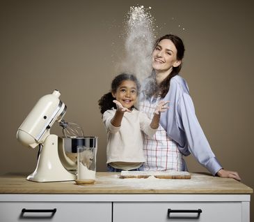 Junge Mutter mit kleinem Kind steht an einer Kücheninsel und backen gemeinsam.