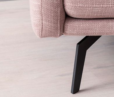 Bildausschnitt von rosanem Stoffsofa mit Fokus auf Fuß