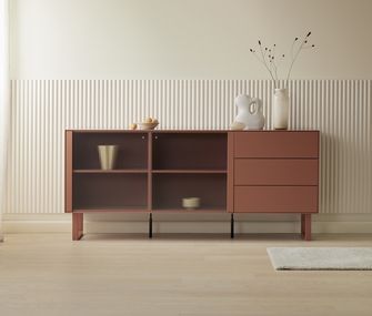 Sideboard mit Schubladen und Riffelglas Türen in Terracotta vor beiger Paneelwand