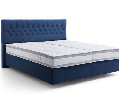 Amerikanische Boxspringbetten haben den Topper in der dicken Obermatratze integriert. Freisteller eines dunkelblauen Boxspringbettes mit amerikanischen Aufbau ohne Topper