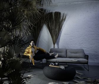 Outdoor-Sofa aus Rope-Geflecht mit passendem Tisch und Model und Palmwedel-Deko.