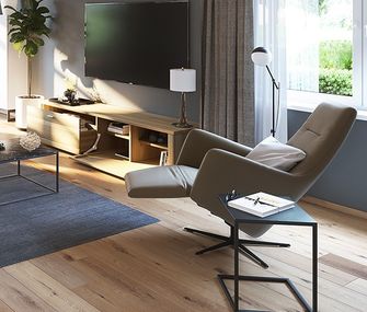 Schwarzer Überstelltisch neben Relaxsessel im steingrauen Lederbezug vor Lowboard mit TV