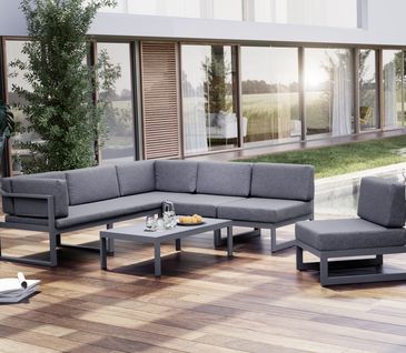 Terasse mit braunem Holzboden, auf der eine graue Sitzlounge mit grauen Polstern und ein grauer dazu passender Sessel und Tisch stehen.