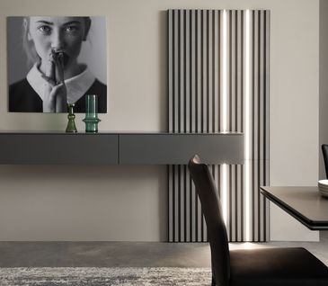 Minimalistische Wohnwand in Anthrazit mit beleuchteter Lamellenwand neben Essbereich.