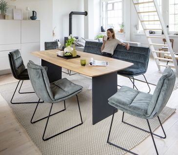 Esszimmer mit Esstisch, vier gepolsterten Stühlen und einer Bank in blauem Stoff.