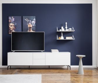 Zwei weiße Wandregale an einer blauen Wand über einem weißen Lowboard