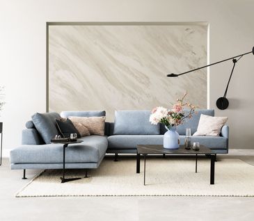 Wohnzimmer mit hellblauem Ecksofa und schwarzem Couchtisch.