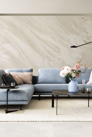 Wohnzimmer mit hellblauem Ecksofa und schwarzem Couchtisch.