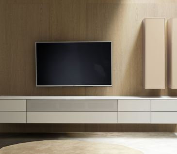 Minimalistische Wohnwand in Weiß und Kaschmir mit Flachbildfernseher.