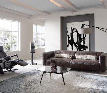 Modernes Wohnzimmer mit braunem Ledersofa und schwarzem Relaxsessel.