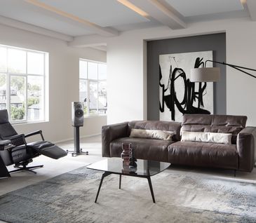 Minimalistisches Wohnzimmer mit dunklem Ledersofa und schwarzem Relax-Sessel.