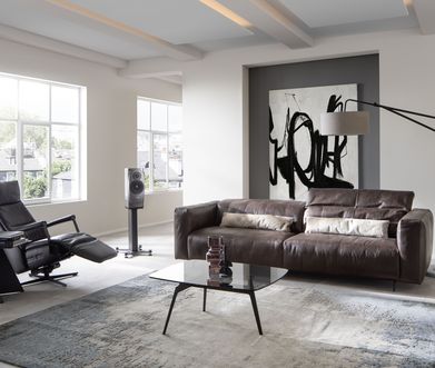 Minimalistisches Wohnzimmer mit dunklem Ledersofa und schwarzem Relax-Sessel.