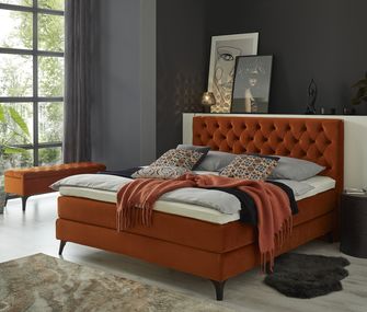 Bett Belina in Terrakotta mit passender Deko vor dunklen Schlafzimmerwänden