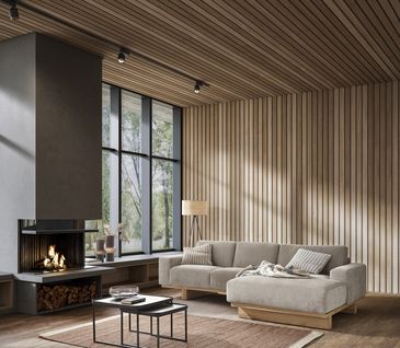 Natürlich eingerichtetes Wohnzimmer mit beigem Ecksofa vor holzverkleideter Wand neben Kamin.