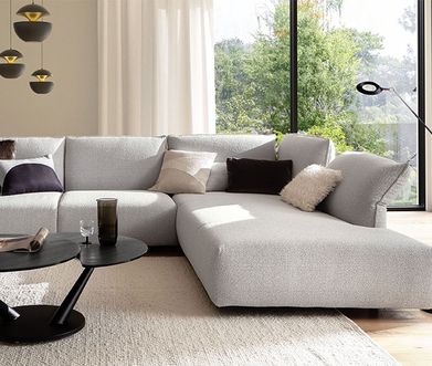Herrlich bequeme Ecksofas bei Homepoet entdecken! Hellgraues Ecksofa in luxuriösem Wohnzimmer mit modernen Lampen und schwarzem Beistelltisch.