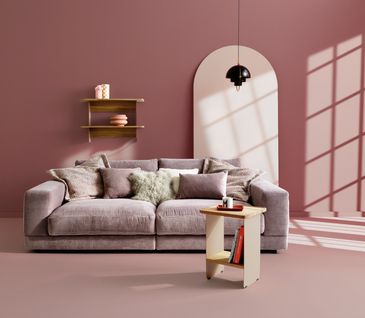 Modernes Wohnzimmer komplett in Rosa mit Cordsofa, Wandregal und Beistelltisch.