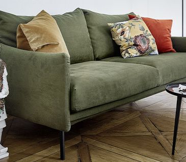 Grünes 2-Sitzer Sofa mit bunten Deko-Kissen und zwei runden Beistelltischen