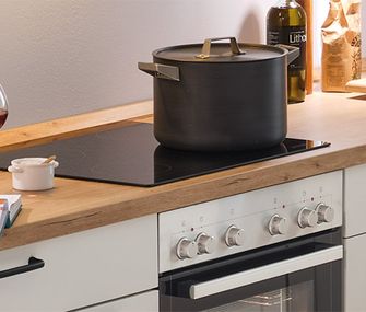Kochen in einer Küchenzeile mit Glaskeramikkochfeld und Backofen