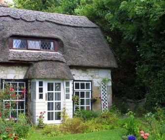 Kleines Landhaus im Grünen mit Steinmauer und vielen Pflanzen