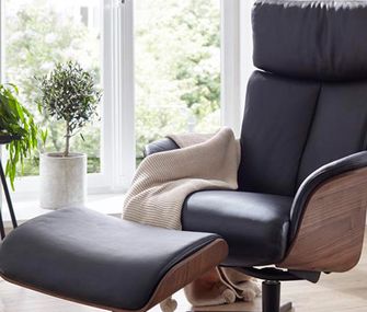 Ledersessel sind zeitlose Klassiker und sorgen für sofortige Eleganz im Wohnzimmer Schwarzer Lederrelaxsessel mit Armlehnschale aus Holz und dem dazu passenden Hocker