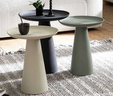 Runde Beistelltische in Beige, Mint und Dunkelblau mit beigem Sofa im Hintergrund auf Teppich.