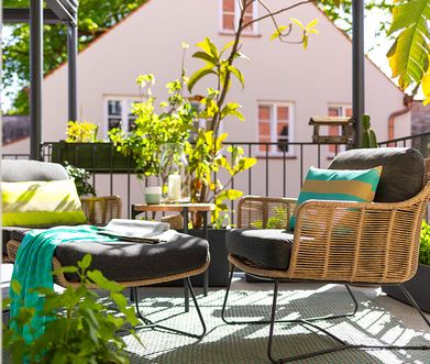 Zwei Gartensessel mit passendem Hocker auf sonnigem Balkon.