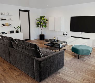 Kleines Cordsofa vor weißer Wohnwand und schwarzem Couchtisch