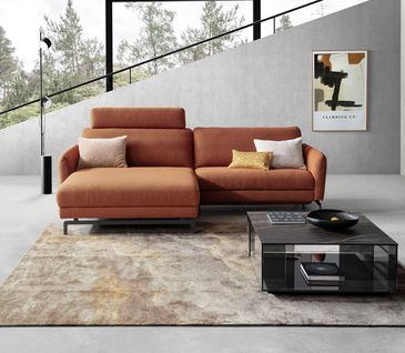 Ecksofa in Rostrot/Terrakotta vor grauer Betonwand in modernem Design Interior mit Marmor Couchtisch