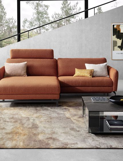 Ecksofa in Rostrot/Terrakotta vor grauer Betonwand in modernem Design Interior mit Marmor Couchtisch