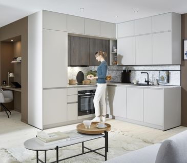 Hellgraue Eckküche in Wohnraum mit Sitzecke und Home-Office Platz.