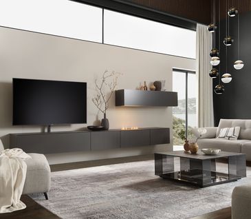 Großzügiges, modernes Wohnzimmer mit minimalistischer Wohnwand in Schwarz, grauem Sofa, Sessel und Couchtisch.