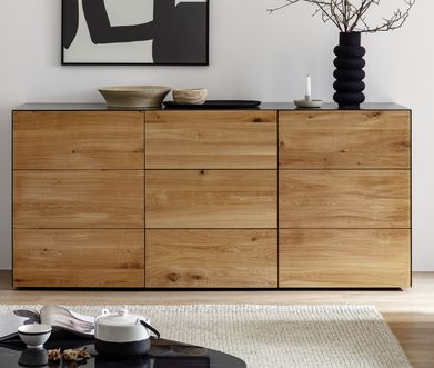 Sideboard aus Massivholz und schwarzem Metall mit moderner Deko und Vase.